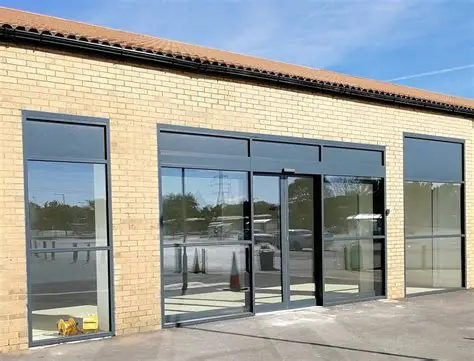 “Modern commercial building with powder‑coated aluminium shopfront frames and large glass panels, showcasing durability and sleek design.”