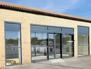 “Modern commercial building with powder‑coated aluminium shopfront frames and large glass panels, showcasing durability and sleek design.”